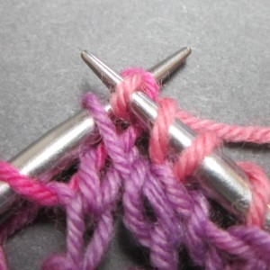 Pull the loop of yarn for the knit stitch through the second stitch.