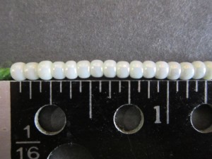 Count side-by-side beads strung on yarn to determine number of beads in an inch